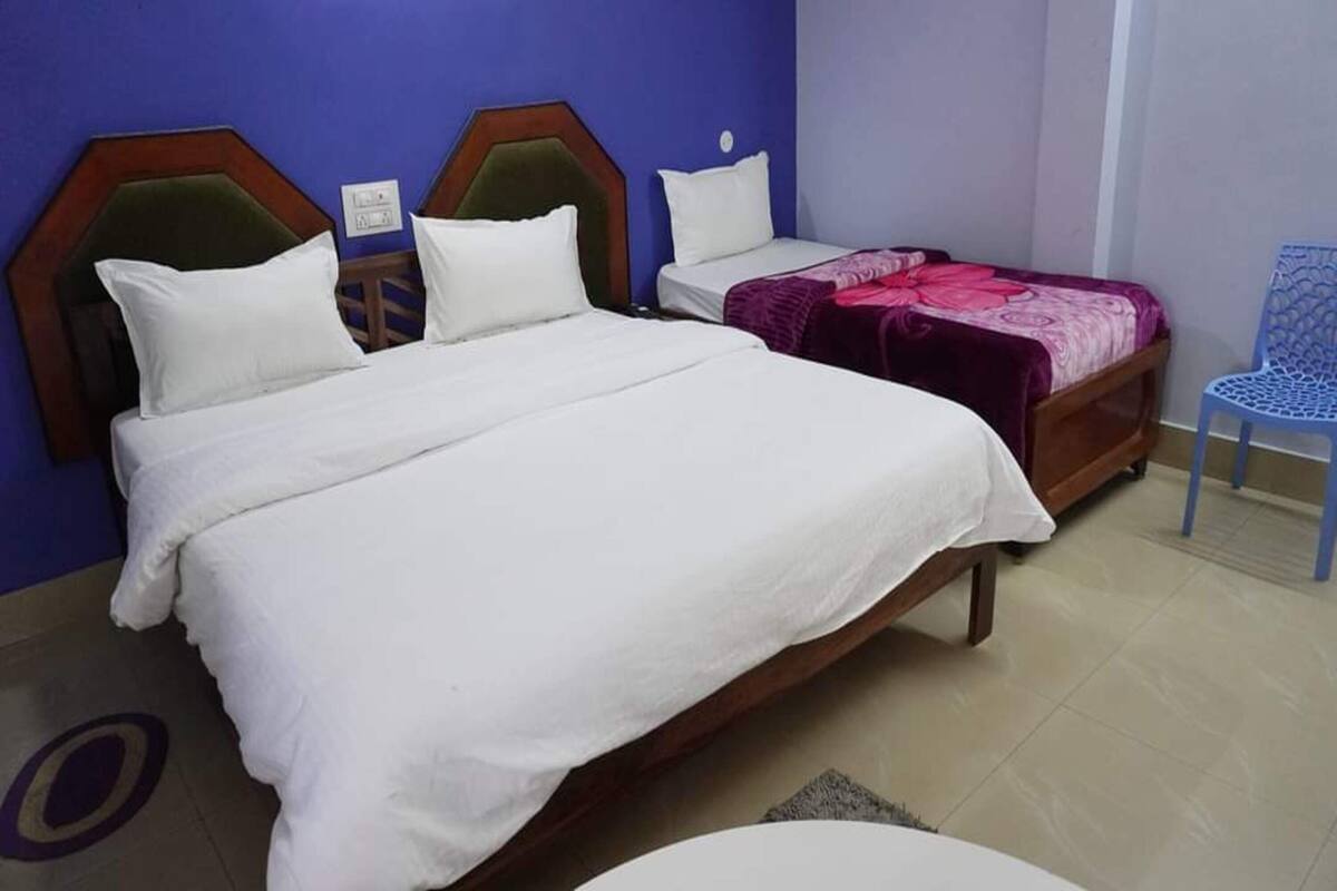 A bedroom with a large bed, a smaller bed, and a chair.