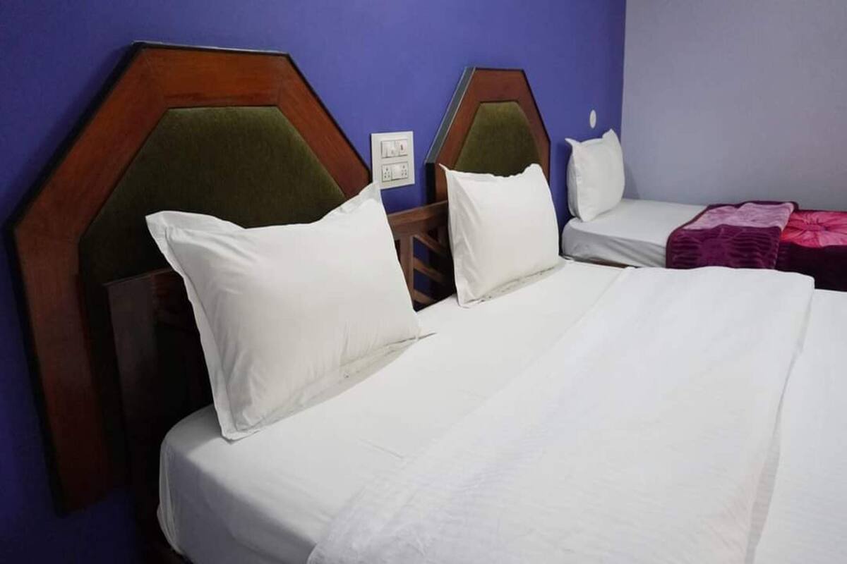 A hotel room with two beds, each with a wooden headboard and green upholstered headboards.