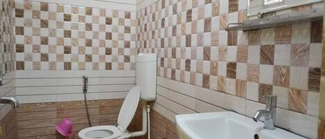 A bathroom with a tiled floor, a toilet, a sink, and a shower area.