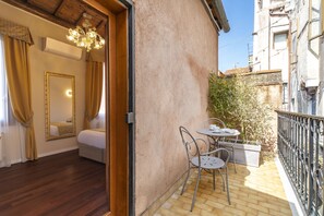 Une pièce avec un plancher en bois, un lit, un grand miroir et un balcon équipé d’une table et de chaises.
