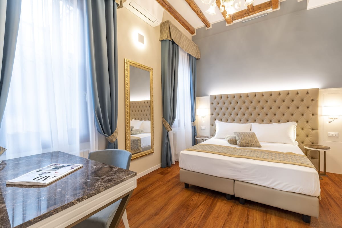 Een hotelkamer met een groot bed, een bureau met een tijdschrift en een spiegel.