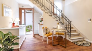 A staircase with ornate metal railings, a round table with a lamp, and a chair with cushions.