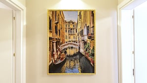 A corridor with a framed painting of a canal scene.