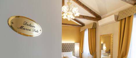 A hotel room with a bed, a chandelier, a mirror, and curtains.
