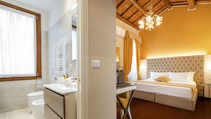 A modern bathroom with a toilet, sink, and towel rack. The room has wooden flooring and a large window with curtains.