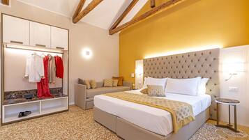 A bedroom with a large bed, a wardrobe, a seating area, and a small table.