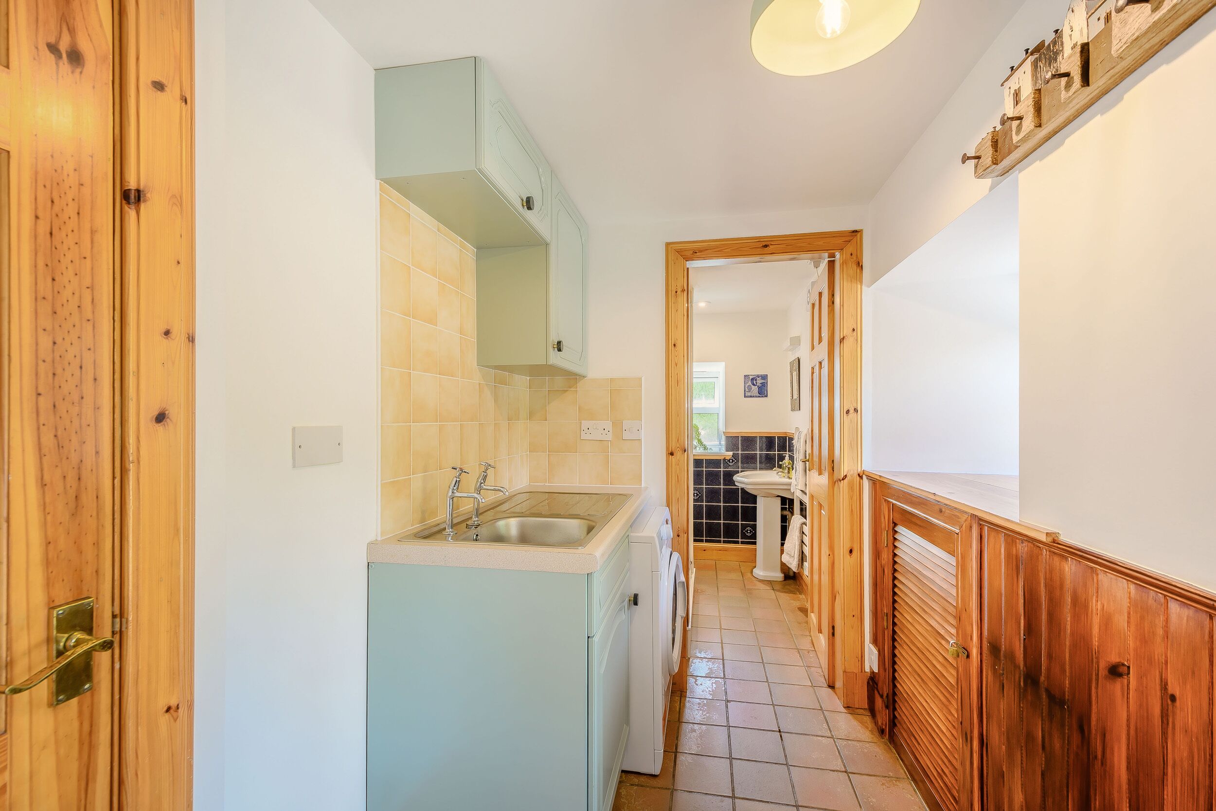 A narrow hallway with a kitchen area on the left, including a sink and washing machine.
