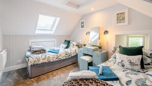 A bedroom with a bed, bedside table, dresser, and a window. - Smithy House (Lochgilphead)