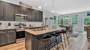 Una cocina moderna con armarios oscuros, electrodomésticos de acero inoxidable y una isla grande con taburetes de bar.