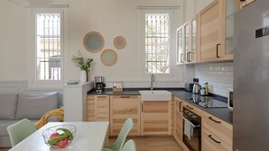 Een moderne keuken met houten kastjes, een roestvrijstalen koelkast en een eethoek met een tafel en stoelen.