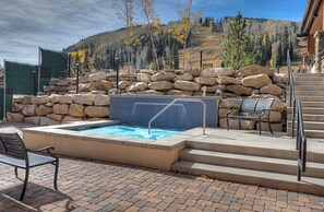 A pool area with a stone wall, a pool with a blue tiled edge, and a bench. - Affordable townhome at Purg - Deck w/Awesome views - Steps to slopes (Durango)