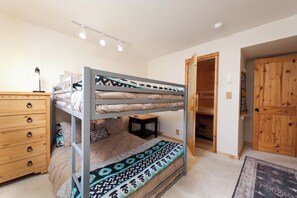 A bunk bed room with a dresser, a small table, and a wooden door. - Affordable townhome at Purg - Deck w/Awesome views - Steps to slopes (Durango)