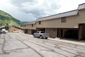 A modern building with a metal roof, a parking lot, and a mountainous backdrop. - Affordable townhome at Purg - Deck w/Awesome views - Steps to slopes (Durango)