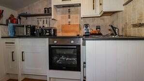 A kitchen with white cabinets, a black oven, a microwave, and a coffee maker.