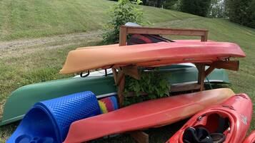 Des kayaks et un grand bac en plastique bleu sur une colline herbeuse.
