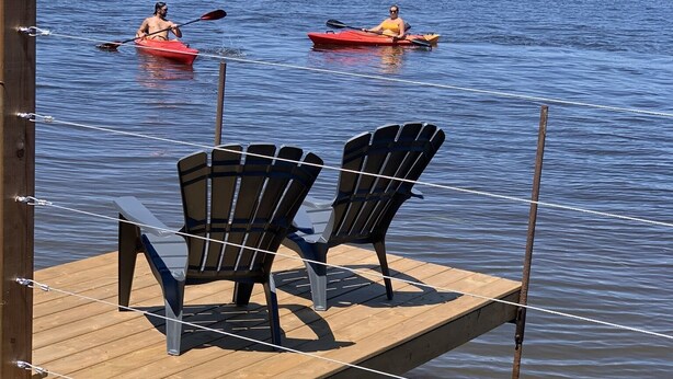 A wooden dock with two Adirondack chairs facing a calm lake. - Glamping in the Captain’s Quarters! (Wendover)