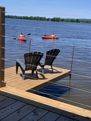A wooden dock with two Adirondack chairs facing a calm lake. - Glamping in the Captain’s Quarters! (Wendover)