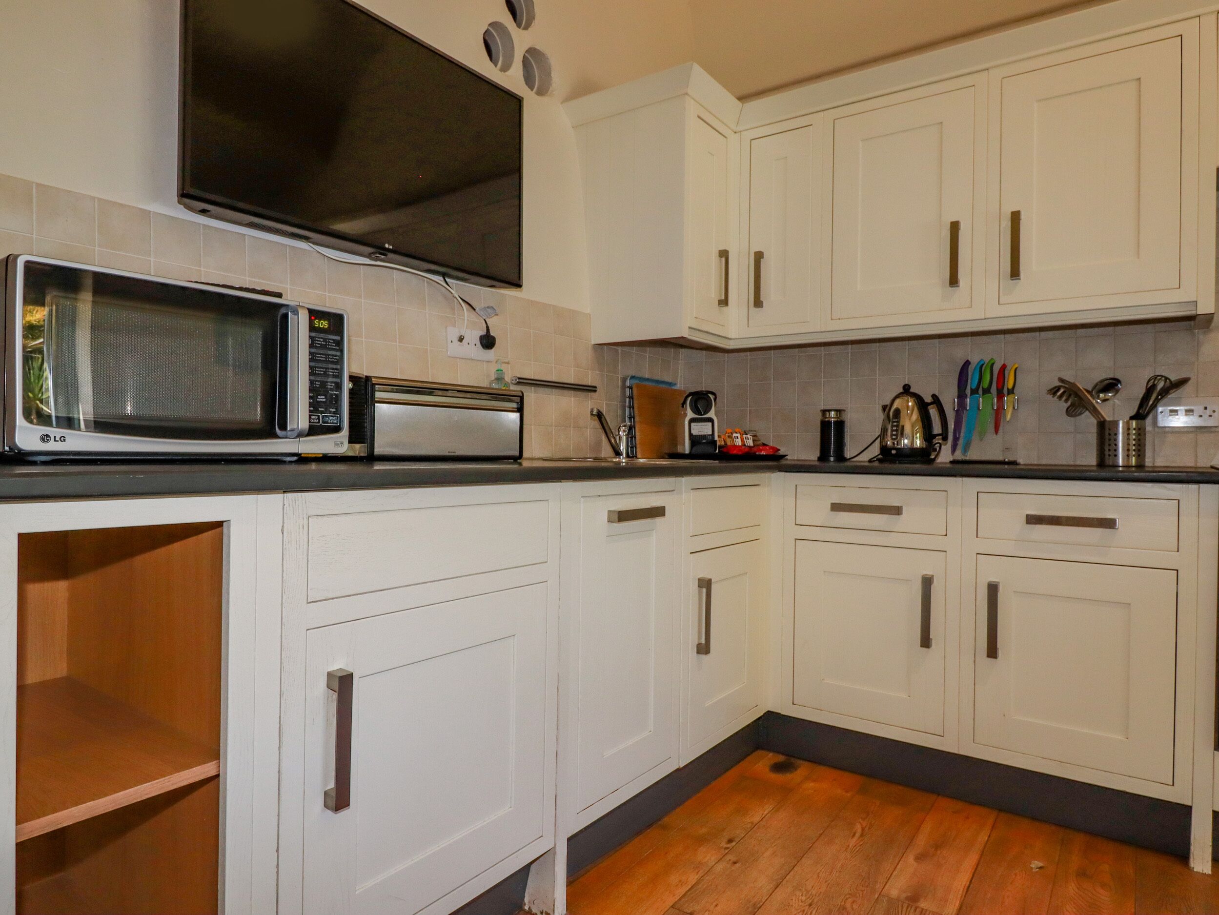 A kitchen with white cabinets, a microwave, a toaster, and a coffee maker.