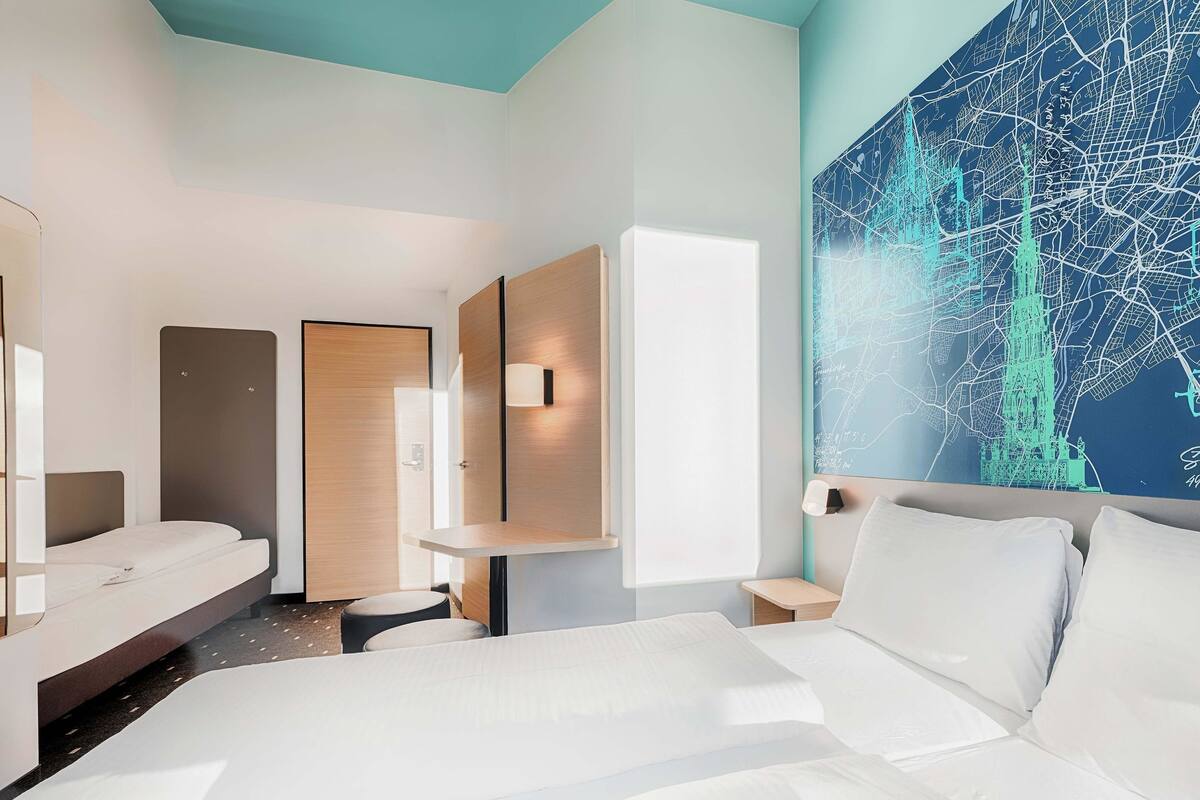 A modern hotel room with a large bed, a desk, and a wall-mounted map.