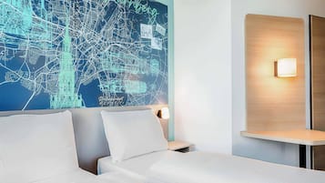 Ein Hotelzimmer mit einer großen Stadtkarte an der Wand, einem Bett mit weißen Laken und einem Nachttisch mit Lampe.