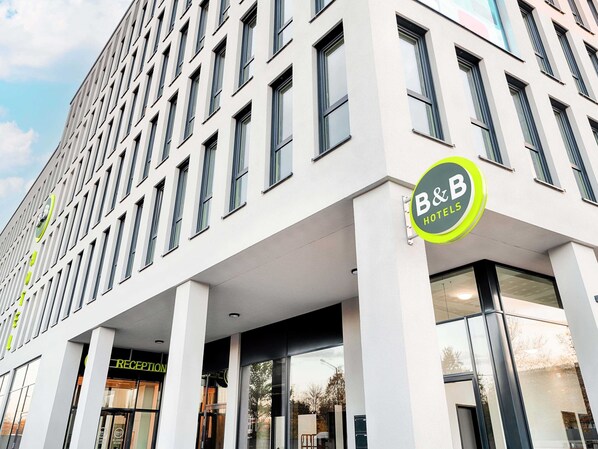 A modern hotel building with a prominent B&B logo, large windows, and a reception area. - B&B Hotel Nürnberg-West (Nuremberg)