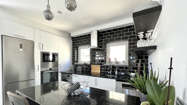 A modern kitchen with a black and white color scheme, stainless steel appliances, and a central island with seating. - Nancy Apartment - Near Vilamoura marina by HD PROPERTIES (Vilamoura)