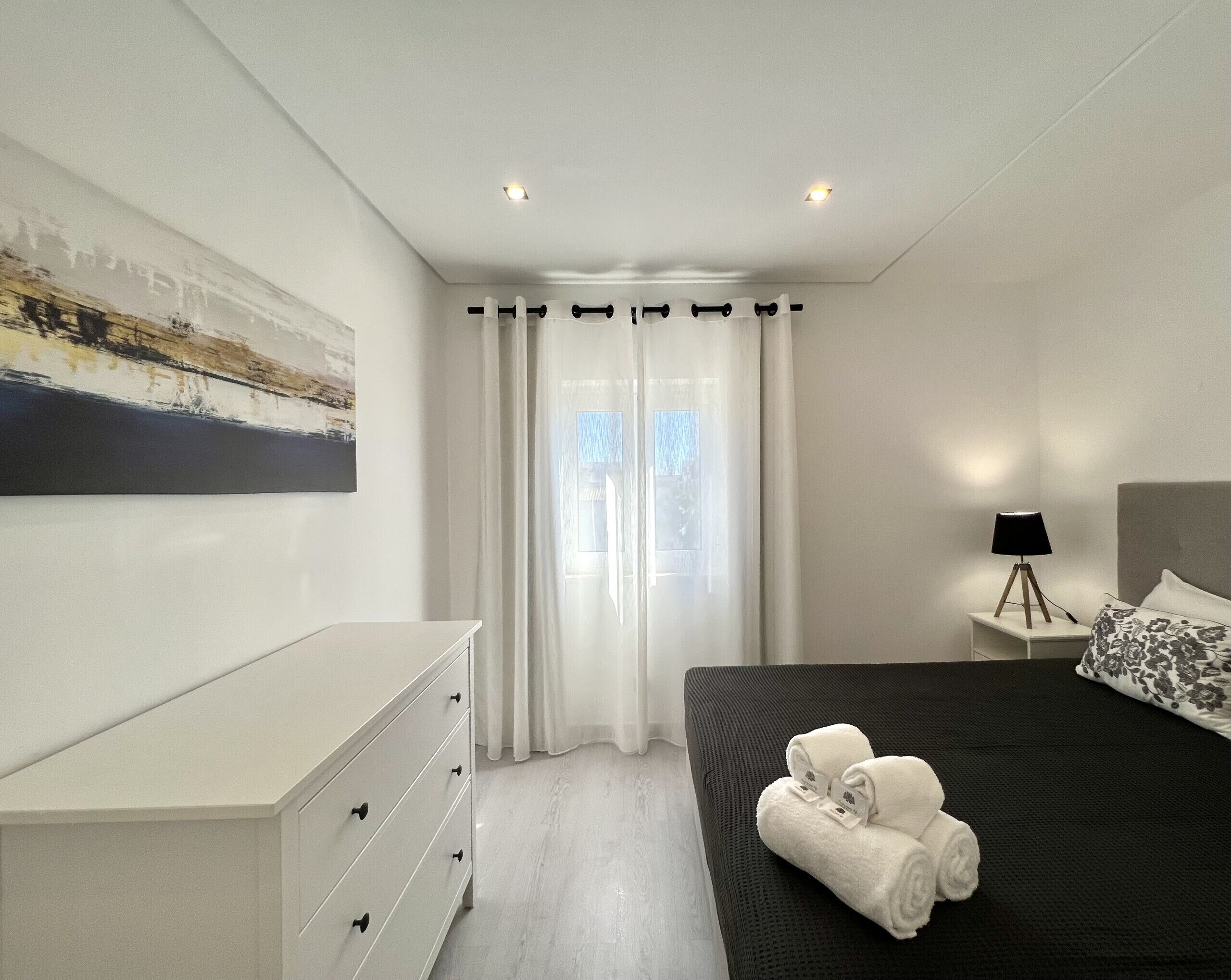 Un dormitorio moderno con una cama, una mesita de noche, una lámpara y un cuadro en la pared.