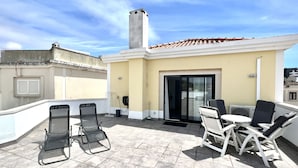 A rooftop terrace with a tiled floor, two lounge chairs, a small table, and a sliding glass door leading to an indoor area. - Nancy Apartment - Near Vilamoura marina by HD PROPERTIES (Vilamoura)