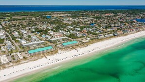 Vista a érea de una ciudad costera con playa, zonas residenciales y un gran hotel con techo azul.