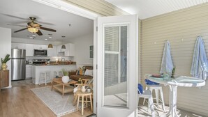 Una cocina moderna con electrodomésticos de acero inoxidable, un comedor con mesa y sillas blancas, y un ventilador de techo.