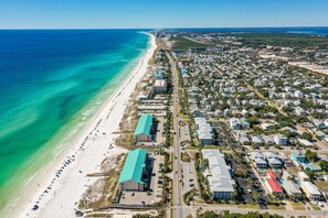 Vue aérienne d’une ville côtière avec une plage, des immeubles résidentiels et une route qui longe la plage.
