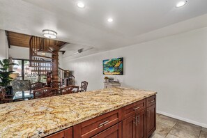 A kitchen with a granite countertop, wooden cabinets, and a spiral staircase.