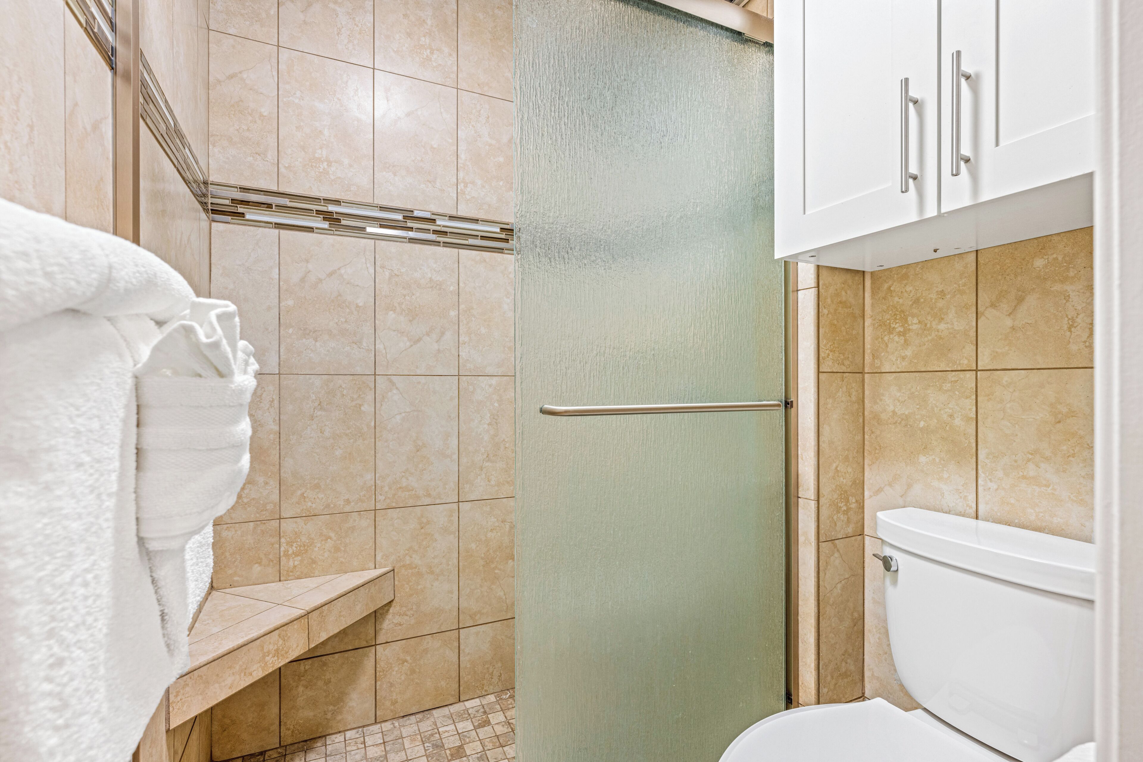 A bathroom with a toilet, a shower, and a towel rack.