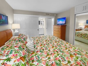 Ein Hotelzimmer mit Bett, Schminktisch, Fernseher und einer Tür zu einem Badezimmer.