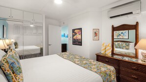 A hotel room with a large bed, a dresser, a mirror, and a wardrobe.