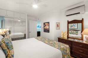 A hotel room with a large bed, a dresser, a mirror, and a wardrobe. - Kihei Surfside #508: Gorgeous Oceanfront Escape with Mesmerizing Views (Kihei, Maui)