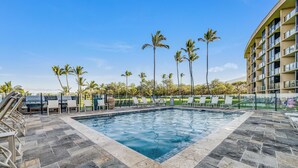 A swimming pool with lounge chairs and palm trees.