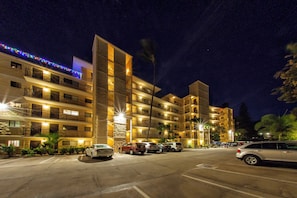 Un hotel de varios pisos con balcones, estacionamiento y luces decorativas.