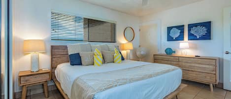 Un dormitorio con cama, mesitas de noche, ventilador de techo, cómoda y decoración en la pared.