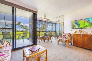 A spacious room with large windows, wicker furniture, and a view of a golf course.