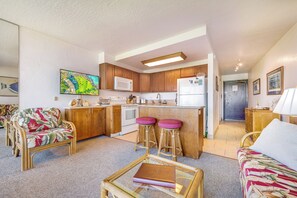 A compact living space with a kitchenette, a sofa, a dining area, and a small bar stool set.