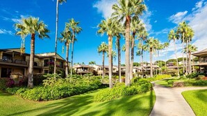 A resort with multiple-story buildings, palm trees, and a well-maintained lawn. - Oceanfront Gem with Mesmerizing Views and Lush Surroundings – Wailea Elua #1404 (Wailea, Maui)