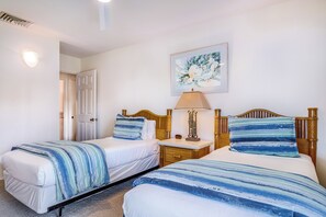 Un dormitorio con dos camas, una mesita de noche, una lámpara y un cuadro en la pared.