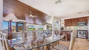 A modern kitchen with wooden cabinets, a stainless steel microwave, and an oven. - Oceanfront Gem with Mesmerizing Views and Lush Surroundings – Wailea Elua #1404 (Wailea, Maui)