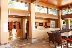 Una cocina amplia con techos altos, ventanas grandes y un comedor con sillas de mimbre.