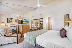 A hotel room with a bed, a desk, a chair, a dresser, and a mirror.