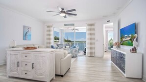 A spacious living area with a large white cabinet, a ceiling fan, and a view of the outdoors. - Coco Cay House on Coco Plum with pool and dock (Marathon)