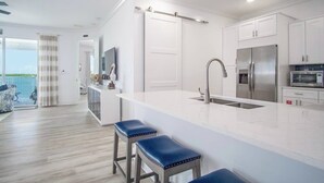 A modern kitchen with a large island, stainless steel appliances, and a view to the outside. - Coco Cay House on Coco Plum with pool and dock (Marathon)