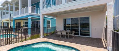 A residential building with a swimming pool, outdoor seating, and a covered patio area.
