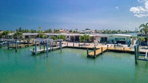 A marina with docked boats, a pool area, and a building with a modern design. - Sea La Vie 2 bedroom on open water in Kcb (Key Colony Beach)
